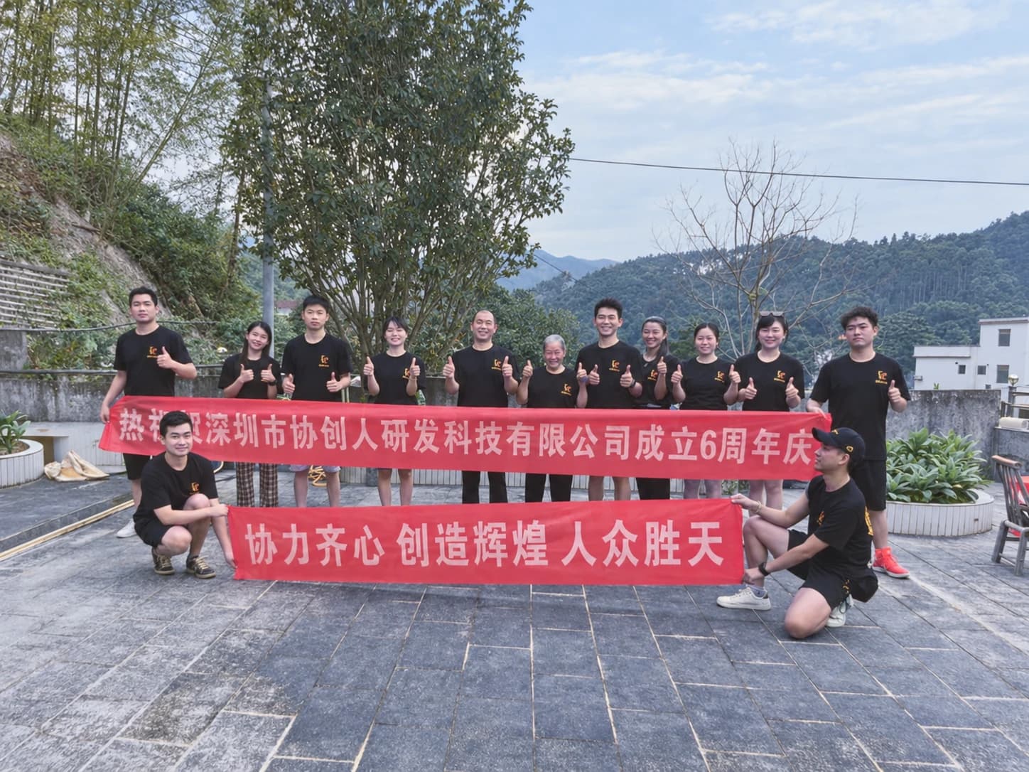 Photo taken at the sixth anniversary event of Co-Creator, with the team holding anniversary banners outdoors